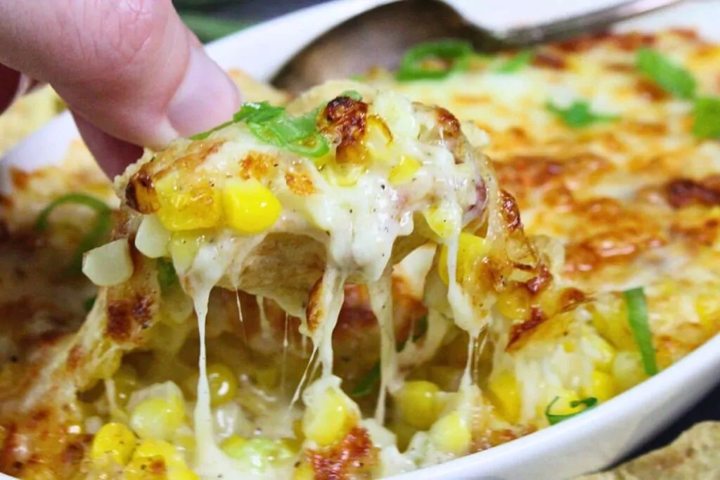 holding up a chip dipped in korean corn cheese showing cheesy pull
