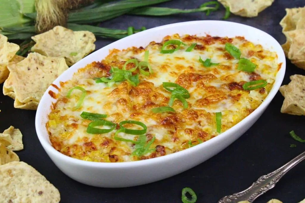 white oval baking dish filled with browned korean corn cheese surrounded by tortilla chips